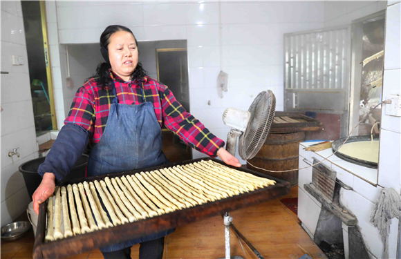 村民把裹好的豆筋端到灶火旁的烘干室去烘干。刘辉 摄