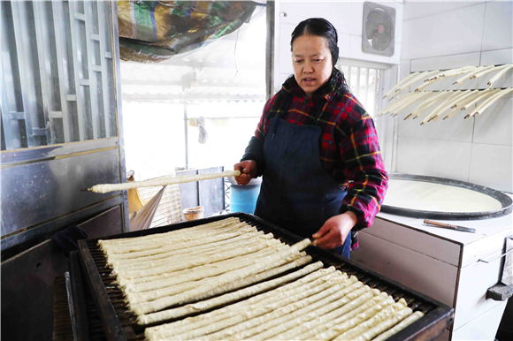 1月27日，梁平区礼让镇同河村8组，村民在把裹好的豆筋放到木箱上。刘辉 摄