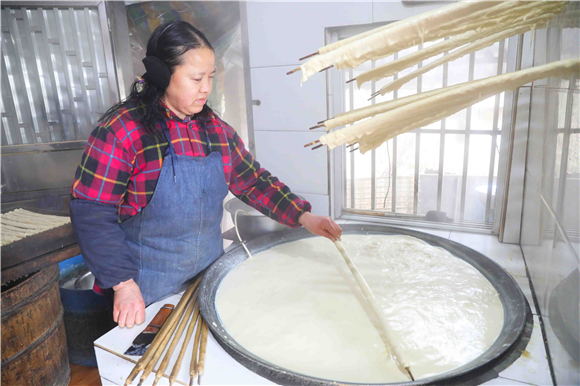 1月27日，梁平区礼让镇同河村8组，村民用竹棍在铁锅内裹豆筋。刘辉 摄